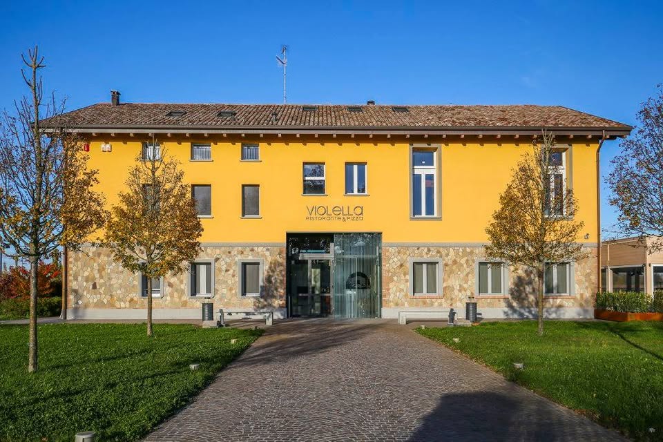 Esterno edificio Violella: facciata gialla con insegna e vialetto in pietra