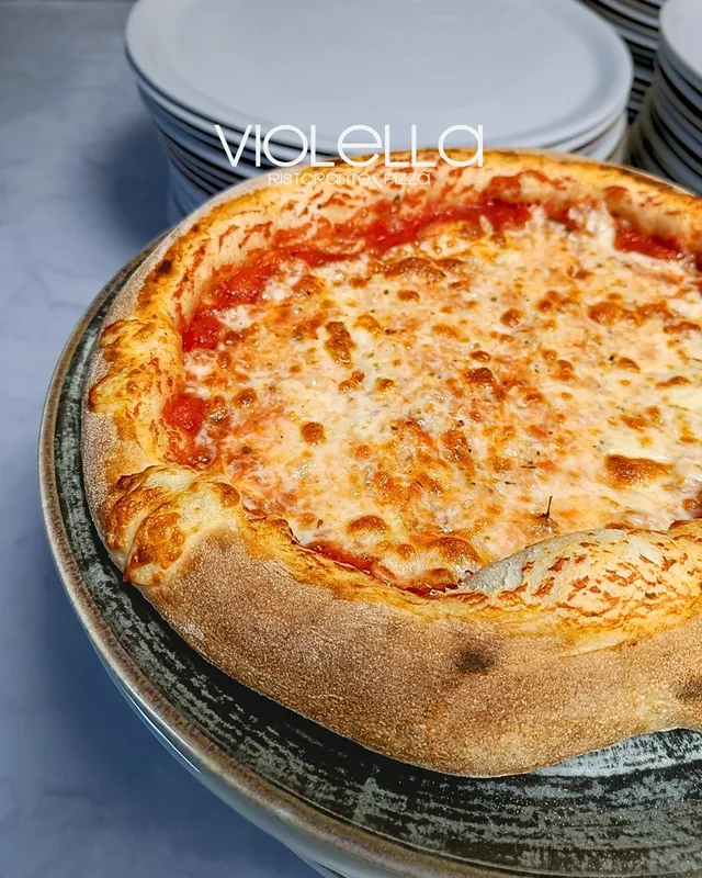 Pizza margherita su piatto in ceramica scura, cornicione dorato